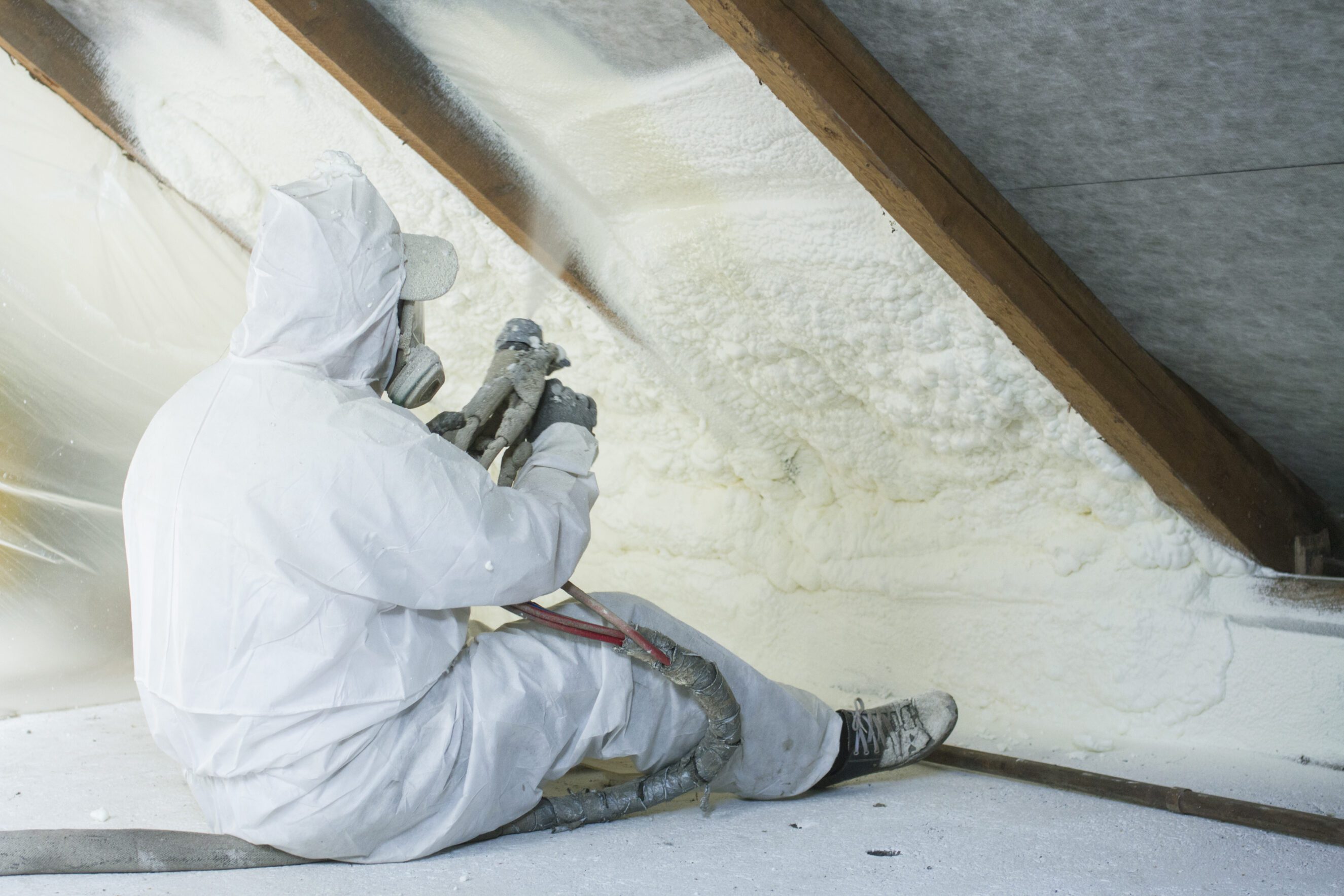 A worker installing spray foam insulation in an attic